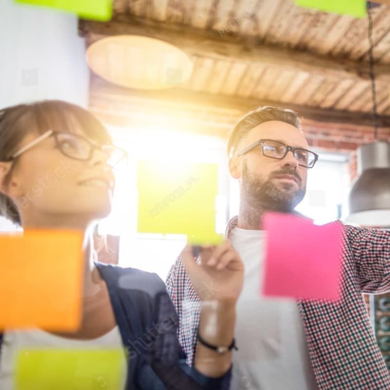 Photograph of people in a creative workshop looking at sticky notes on a wall